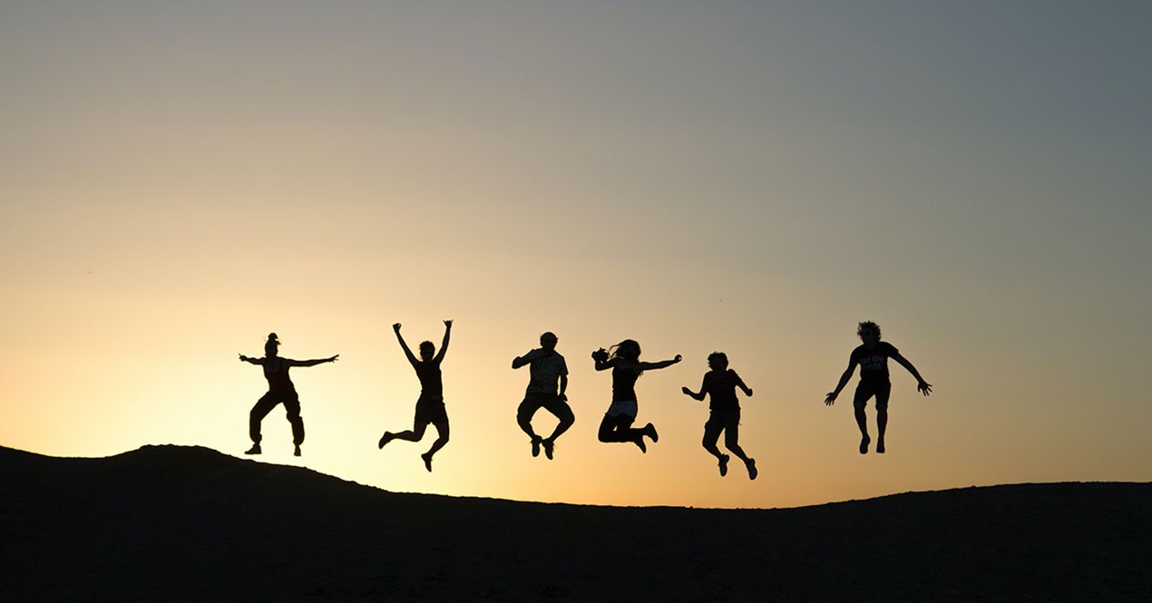 Illustrasjonsfoto av seks unge mennesker som hopper i solnedgang (Foto: Timon Studler | Unsplash).
